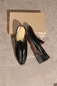 High-quality black patent leather men's loafers featuring a shiny gold insole detail