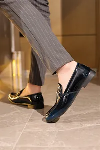 Seitenansicht eleganter schwarzer Herren-Slipper aus Lackleder mit Metallschnalle