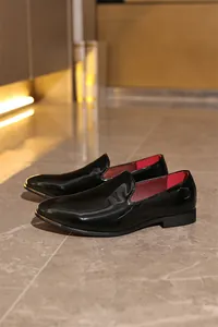 Elegant close-up of glossy black patent leather loafers with red lining on marble floor