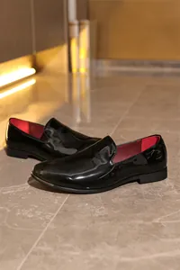 Detailed view of glossy black patent leather loafers with premium red inner lining.