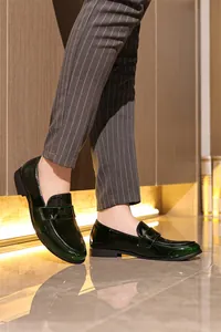 Nahaufnahme von grünen Lackleder-Loafers für Herren mit gestreifter Hose.