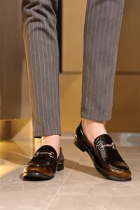 Detailansicht stilvoller Herren-Loafer aus braunem Lackleder mit Metallverzierung.