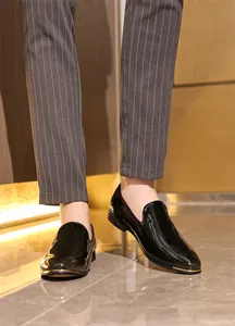 Detailed close-up of glossy black patent leather men's loafers with elegant gold toe trim