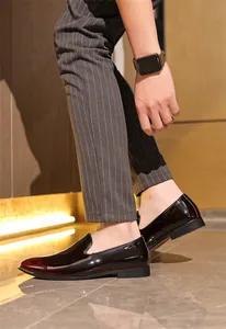 Detail of men's glossy dark burgundy slip-on loafers worn with striped trousers