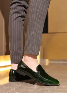 Detail view of dark green patent leather loafers for men in a formal business setting