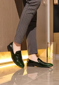 Detail shot of elegant dark green patent leather loafers for men in formal setting.