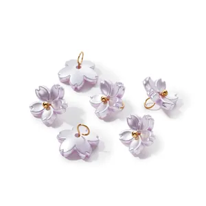 Detailed view of pearlescent purple ABS flower charms with gold loops