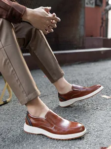 Detail view of brown leather business casual loafers on feet in an outdoor setting