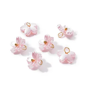 Close-up of pink pearlescent Sakura flower charms with gold loops for DIY jewelry