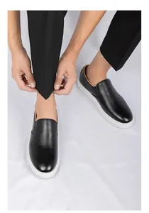 Primer plano detallado de mocasines de cuero negro para hombre con suela blanca.