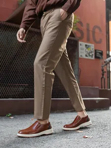Side view of elegant brown leather loafers worn with khaki pants in an urban setting