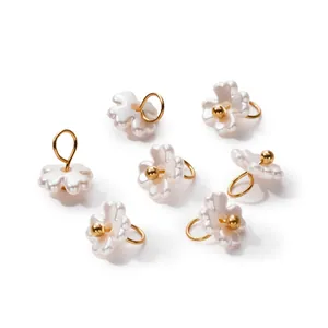 Close-up of pearlescent ABS flower pendants with golden loops for DIY jewelry making
