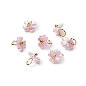 Detailed view of pink iridescent pearl flower pendants with gold loops for DIY jewelry