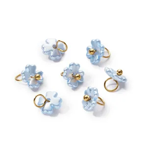 Macro view of blue iridescent 3D flower charms with gold loops for DIY jewelry