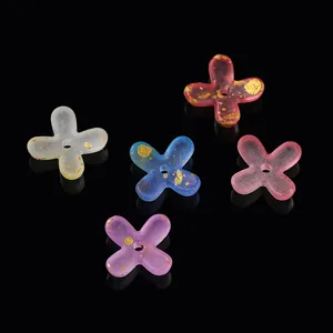Macro view of gradient acrylic flower beads with gold leaf for DIY jewelry making.