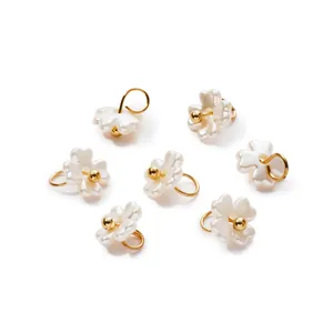 Close-up detail of iridescent white pearl flower pendants with gold rings for DIY jewelry