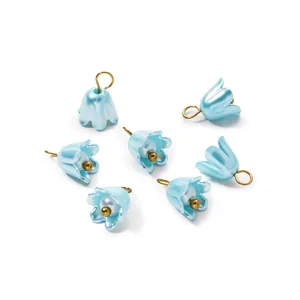 Close-up of elegant blue pearlescent lily flower charms with gold loops for DIY jewelry