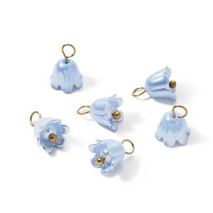 Close-up of iridescent light blue flower charms with golden pearls and loops for DIY.