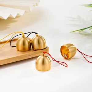 Detailed view of matte brass small bell pendants with colorful hanging ropes for DIY