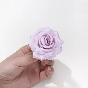Primo piano di una testa di rosa artificiale in seta viola con gocce di rugiada realistiche.
