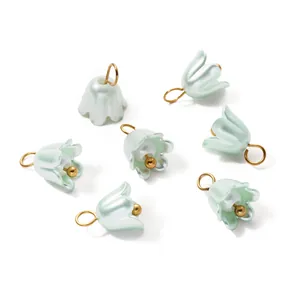 Detailed macro shot of pearlescent mint green lily flower charms with golden jump rings
