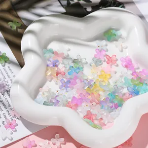 Macro view of colorful acrylic flower beads with gold foil in a white dish.