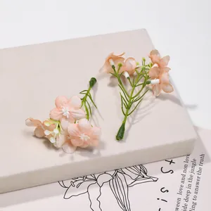 Macro dettagliata di mini fiori in seta fatti a mano color pesca per accessori capelli DIY