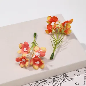 Vista macro dettagliata di due fiori di seta artificiale con petali arancio e giallo.