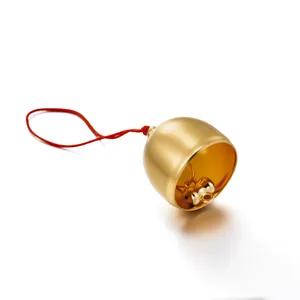 Close-up of matte brass bell pendant with red string DIY accessory