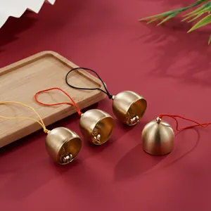Macro shot of matte brass bell pendants featuring colorful hanging strings for DIY decor