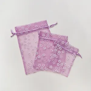Detailopname van drie maten paarse organza zakjes met bloemenpatroon voor cadeaus