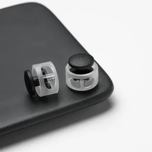 Detailed macro view of transparent plastic spring cord locks with black toggles on a dark board