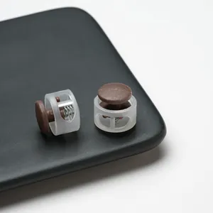 Macro detail of translucent and brown plastic spring cord locks on a black matte surface.