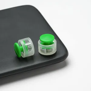 Close-up of green and clear double-hole plastic cord locks for masks and drawstrings