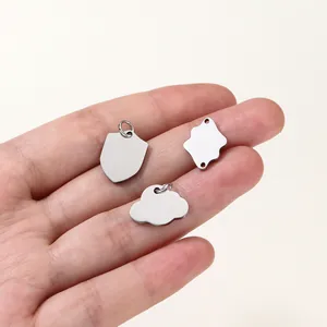 Three small blank stainless steel jewelry charms in various shapes held on a hand