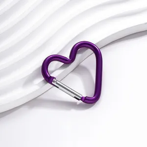 Gros plan d'un mousqueton en aluminium violet en forme de cœur sur un fond blanc texturé