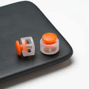 Detail view of orange and transparent round double-hole plastic spring toggle cord locks