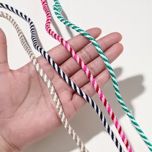 Détail de cordons en coton tressé multicolores tenus à la main pour projets créatifs DIY