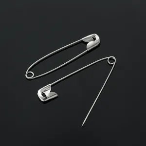 Coppia di classiche spille da balia in metallo argento su superficie riflettente.