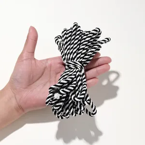 Main tenant une corde en coton tressé torsadé noir et blanc pour le bricolage et l'art