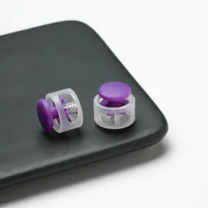 Close-up detail of purple plastic spring cord lock with clear housing and internal spring