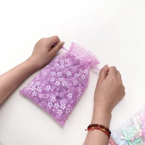 Detailweergave van handen die aan de trekkoorden van een paars organza cadeauzakje trekken