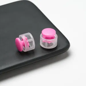 Macro detail of pink and translucent plastic spring cord locks on a black surface