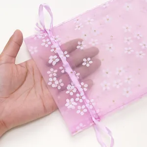 Detailopname van de transparantie en bloemenprint van het roze organza zakje.