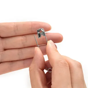 Primo piano di una mano che tiene una spilla da balia in metallo argento antiruggine