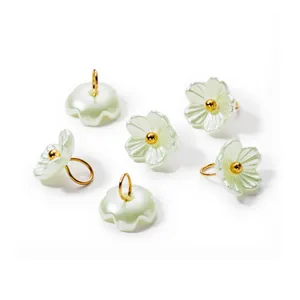 Detailed view of iridescent pearl flower pendants with gold jump rings for DIY crafts
