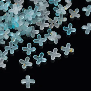 Macro detail of gradient blue and white acrylic four-petal flower beads with gold foil flakes