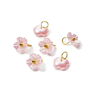 Macro detail of iridescent pearlescent ABS flower charms with golden jump rings