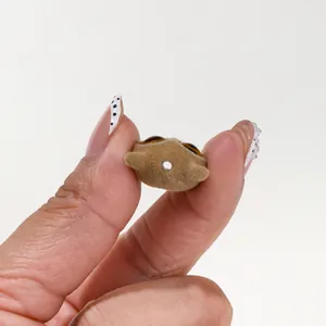 Gros plan d'une perle de chat floquée marron pour bijoux DIY tenue entre les doigts.