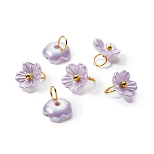 Macro view of iridescent purple pearl flower pendants with gold rings for DIY jewelry